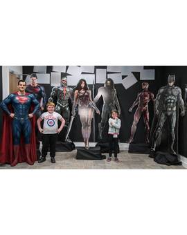 Henry Cavill posando con unos niños de la Fundación Make a Wish y con arte promocional de la Liga de la Justicia