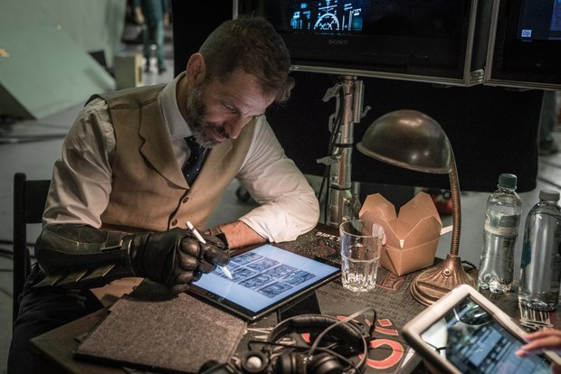 Zack Snyder con unos bocetos de la Liga de la Justicia (con un tío con parche y espadas posiblemente hablando con un tipo sin pelo) 